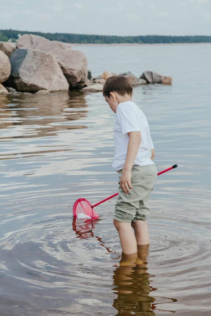 kid wading in water with net