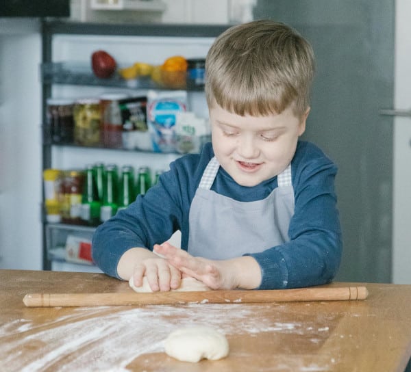 small smiling child kneading bread dough