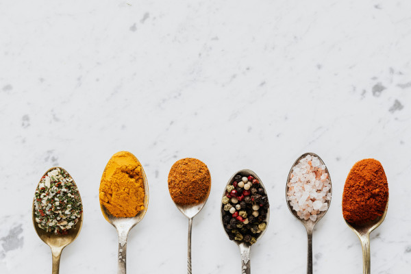 6 spoons with colorful spices on marble background