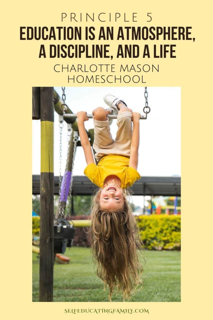 long haired little girl in a yellow shirt hanging upside down on the playground