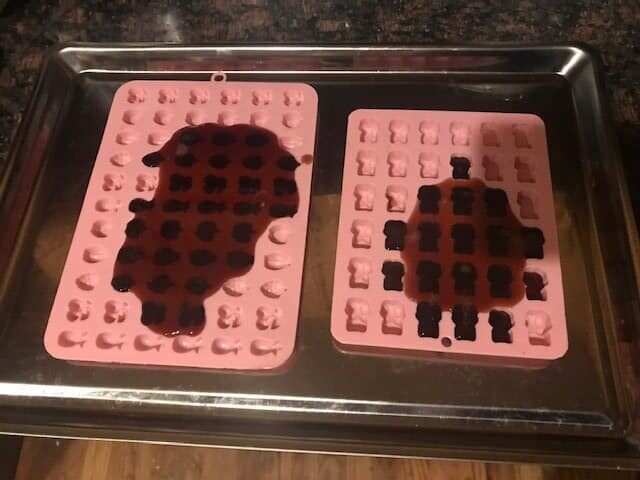 elderberry syrup mixture poured onto silicone molds for shaping as gummies