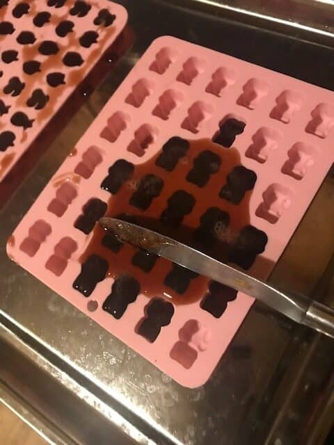 knife scraping elderberry mixture on silicone mold