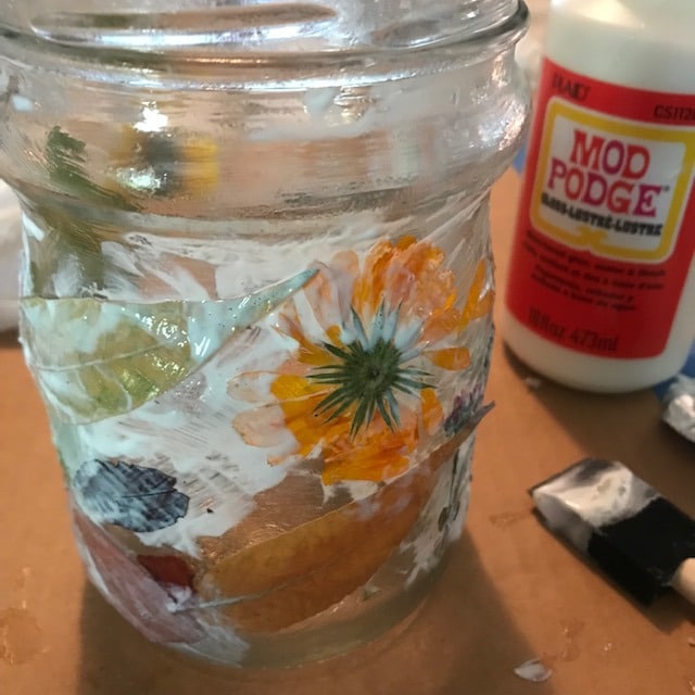 mod podge with flowers and leaves on a jar still wet