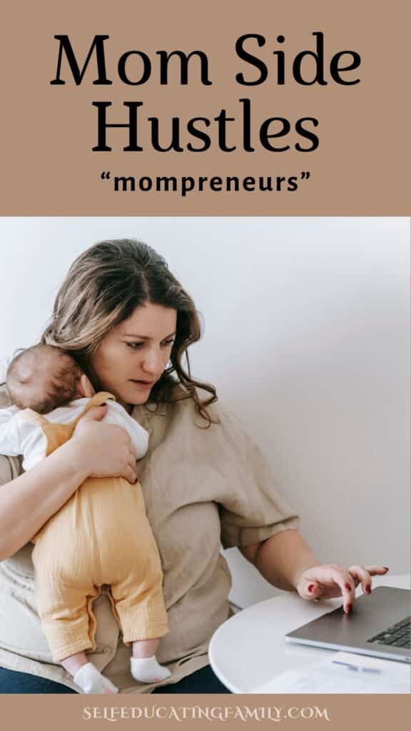 Mom holding baby while typing on computer. She's working on her side hustle as a mompreneur
